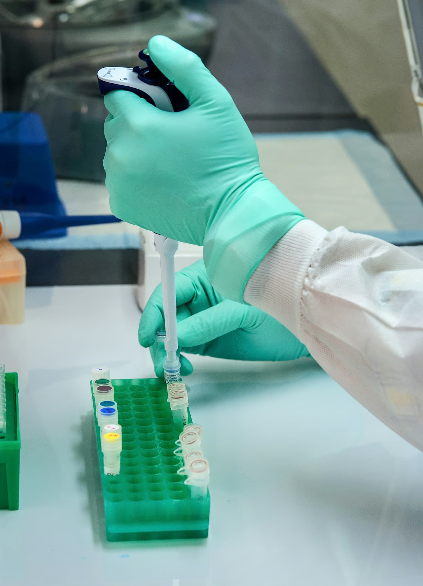 Gloved hands using a pipette to transfer a sample into a vial